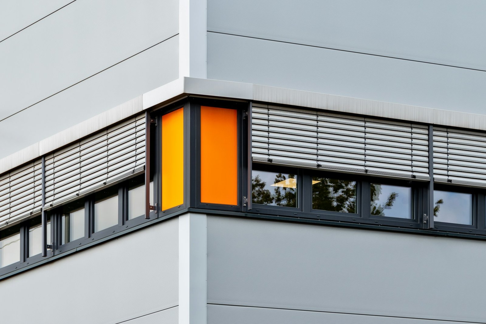 Horizontal shot of a grey building with open windows and grey window blinds